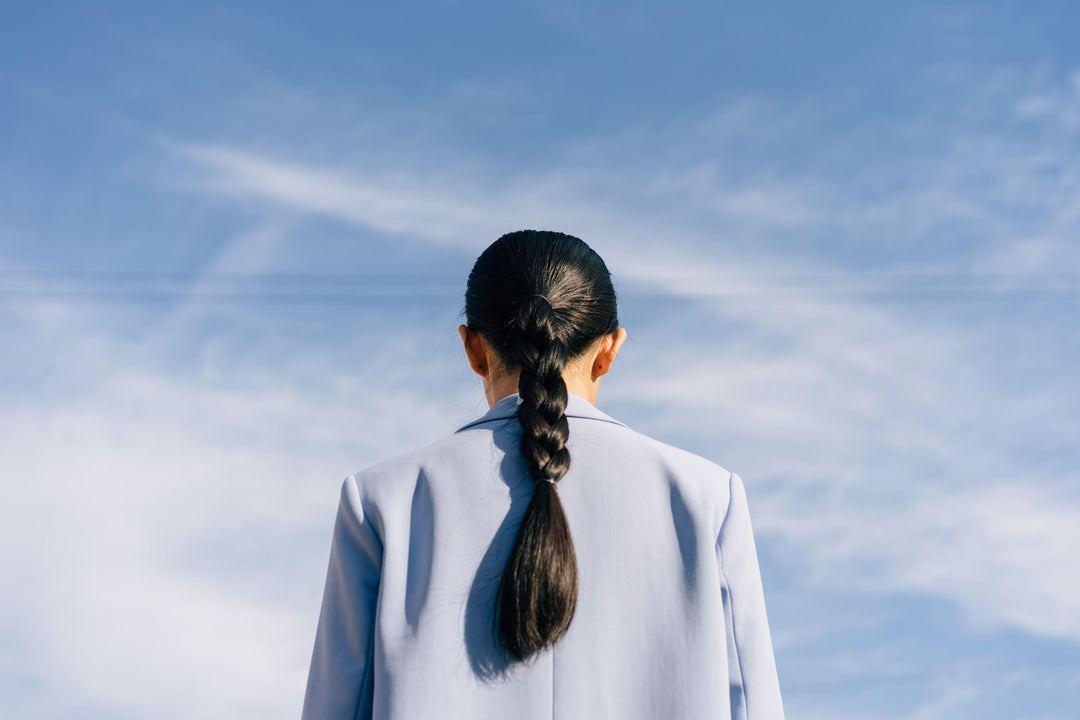 Back view of a woman with a braid against a blue sky
